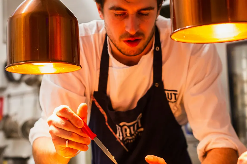 Chef finishing a dish under warm kitchen lights in a professional kitchen